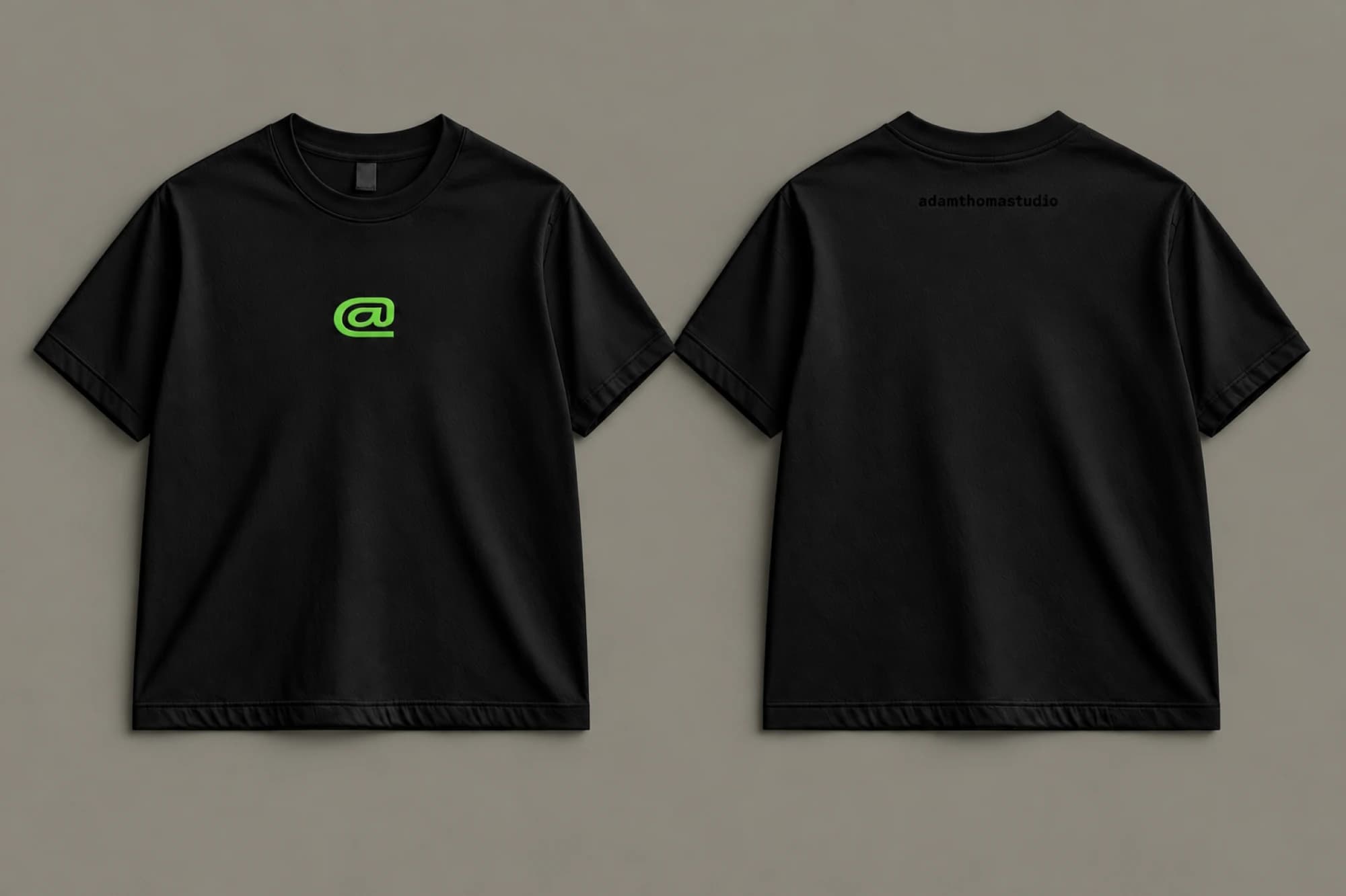 Front and back of the black PROCESS / HACKING T-shirt with a green chest logo and subtle black adamthomastudio lettering below the back neckline.