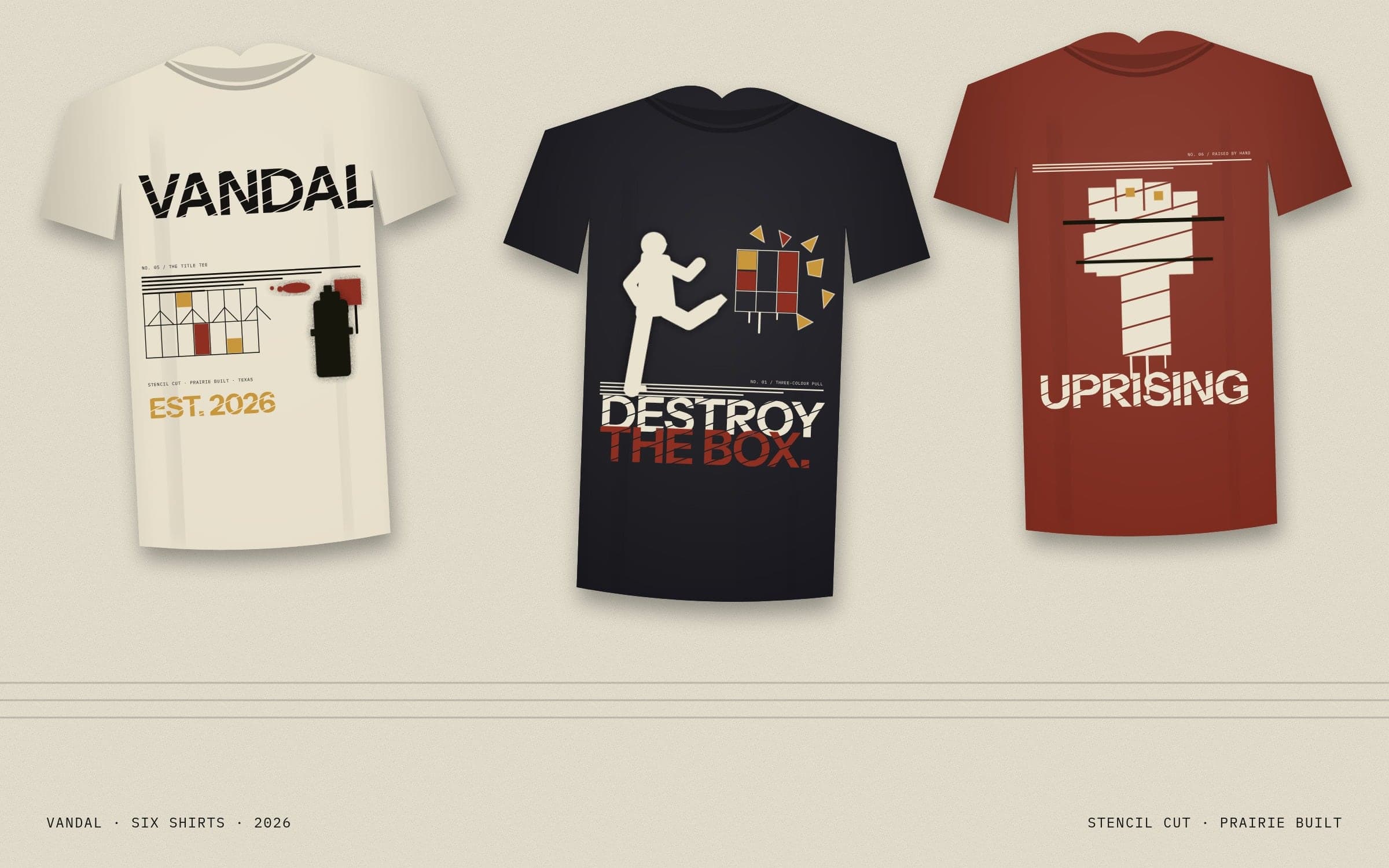 Three Vandal tees laid flat on paper: the cream title tee, Destroy the Box on black, Uprising on Cherokee red